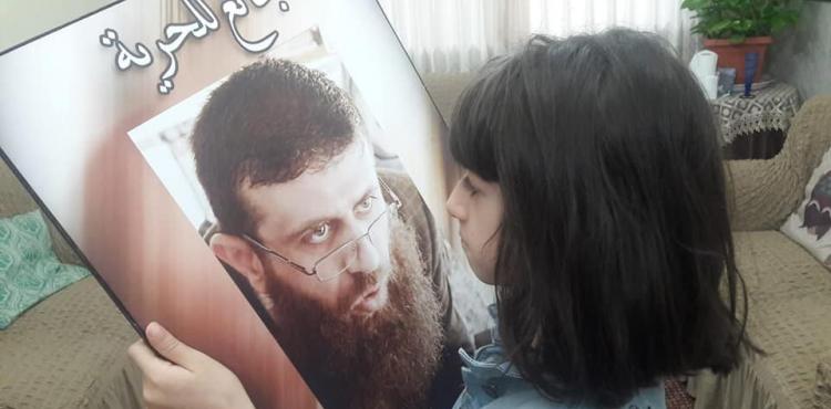 ابن الشيخ خضر عدنان يحمل صورة ابيه.jpg