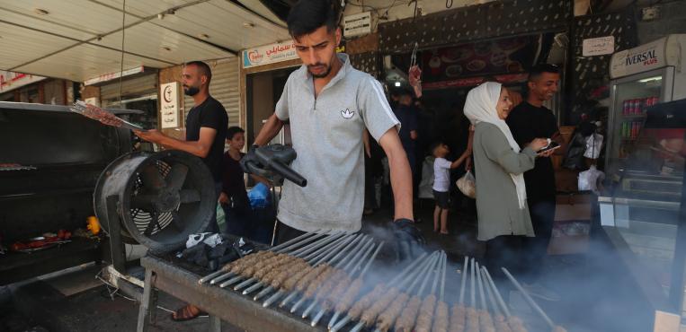 عمال فلسطينيون يشوون الكباب المصنوع من اللحوم المثلجة التي توزعها المؤسسات الخيرية على النازحين، خلال أيام عيد الأضحى المبارك ،