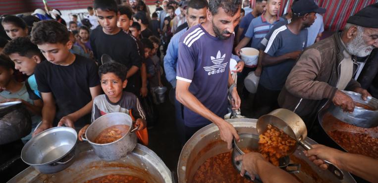 فلسطينيونً يقفون أمام طوابير للحصول علي الطعام التي تقدمه الموسسات الخيرية