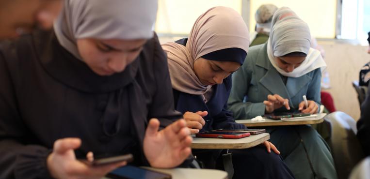 طلاب فلسطينيون يؤدون امتحان شهادة التعليم الثانوي العام (التوجيهي) الإلكتروني في قاعه دراسية