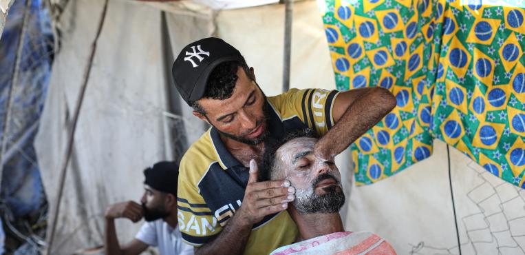 الفلسطيني جهاد المبحوح، 38 عامًا، يعمل بمهنه الحلاقه داخل خيمته، تعرض لبتر في يده جراء إصابته خلال الحرب علي مدينة غزة