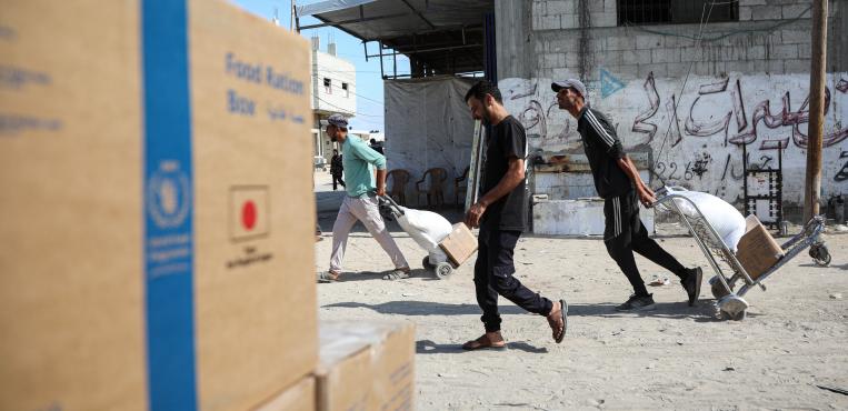 فلسطينيون يتسلّمون طرودًا غذائية من برنامج الأغذية العالمي في غزة، بعد إعلانه تقليص مساعداته في 19 أكتوبر