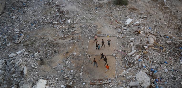 أطفال فلسطينيون يلعبون كرة القدم في أحد الأحياء التي دمرتها الحرب، وسط أنقاض المباني والمنازل في قطاع غزة،